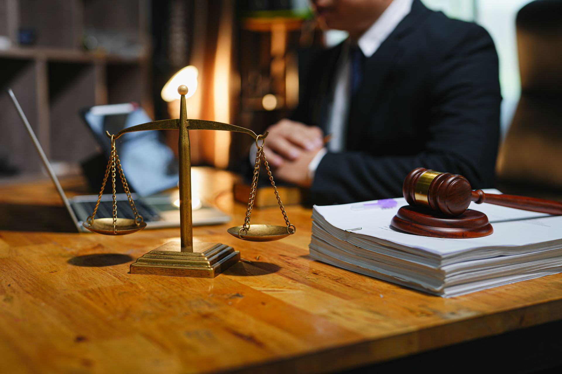 Two people in business suits review a contract and a legal document at a desk in an office.