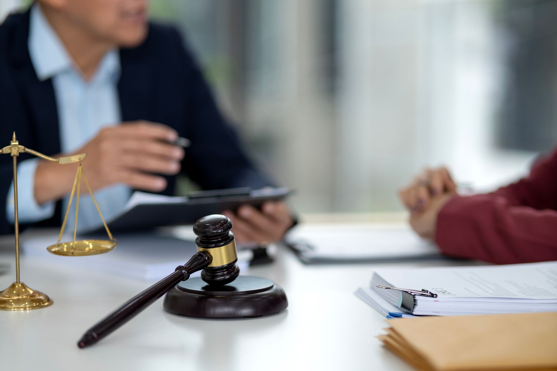 Two people in business suits review a contract and a legal document at a desk in an office.