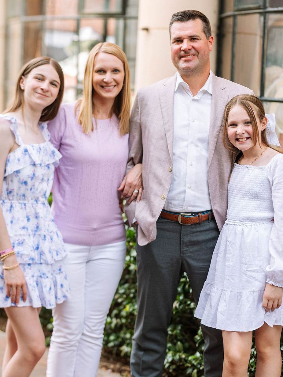 A family is posing for a picture together in front of a building.