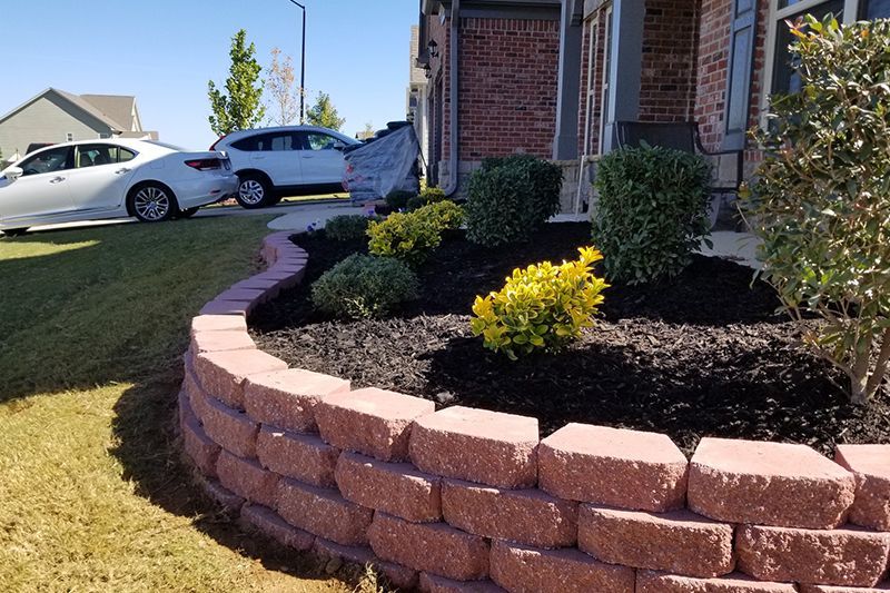 A brick wall surrounds a garden in front of a house