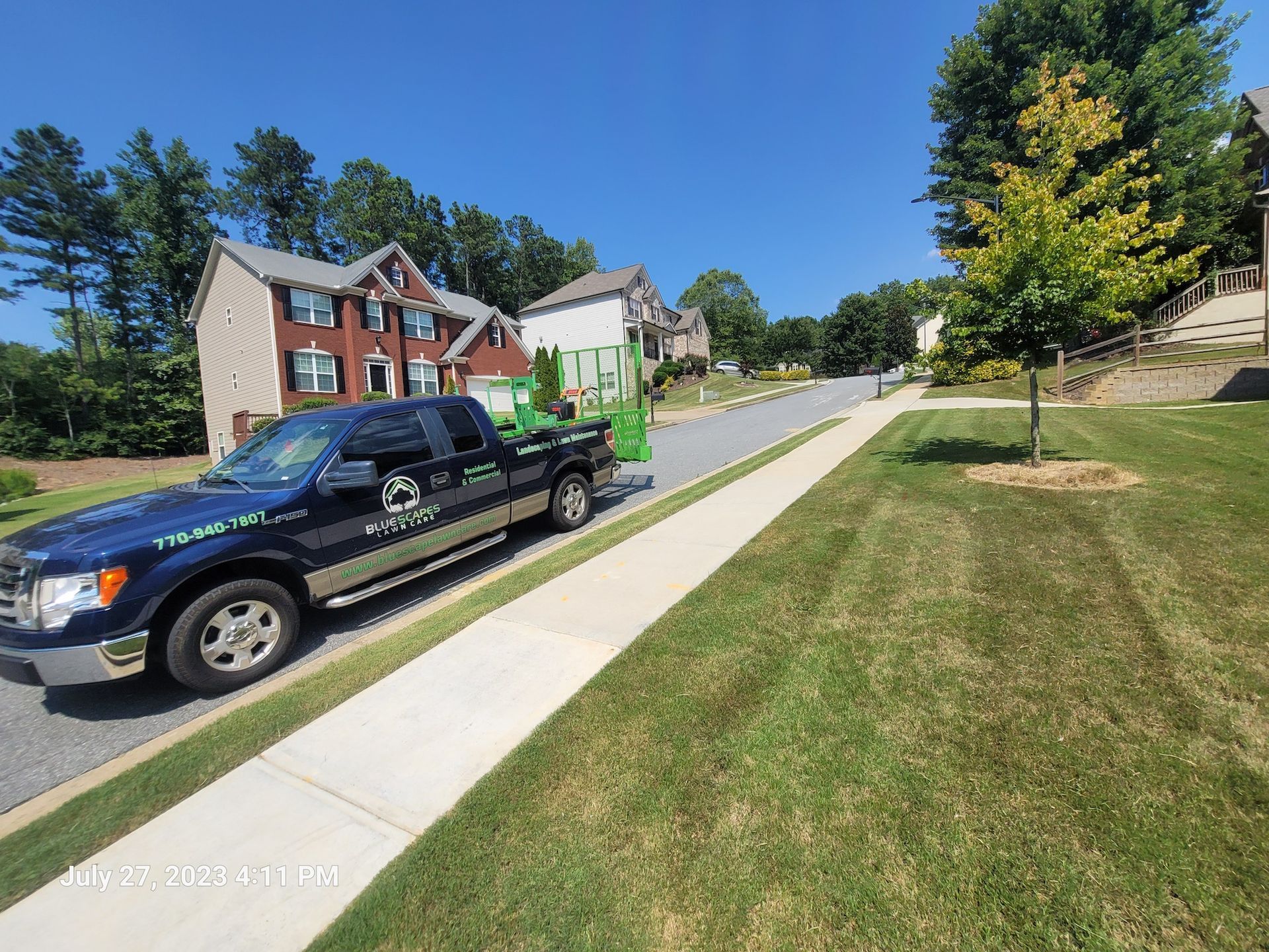 A black truck is parked on the side of the road next to a sidewalk