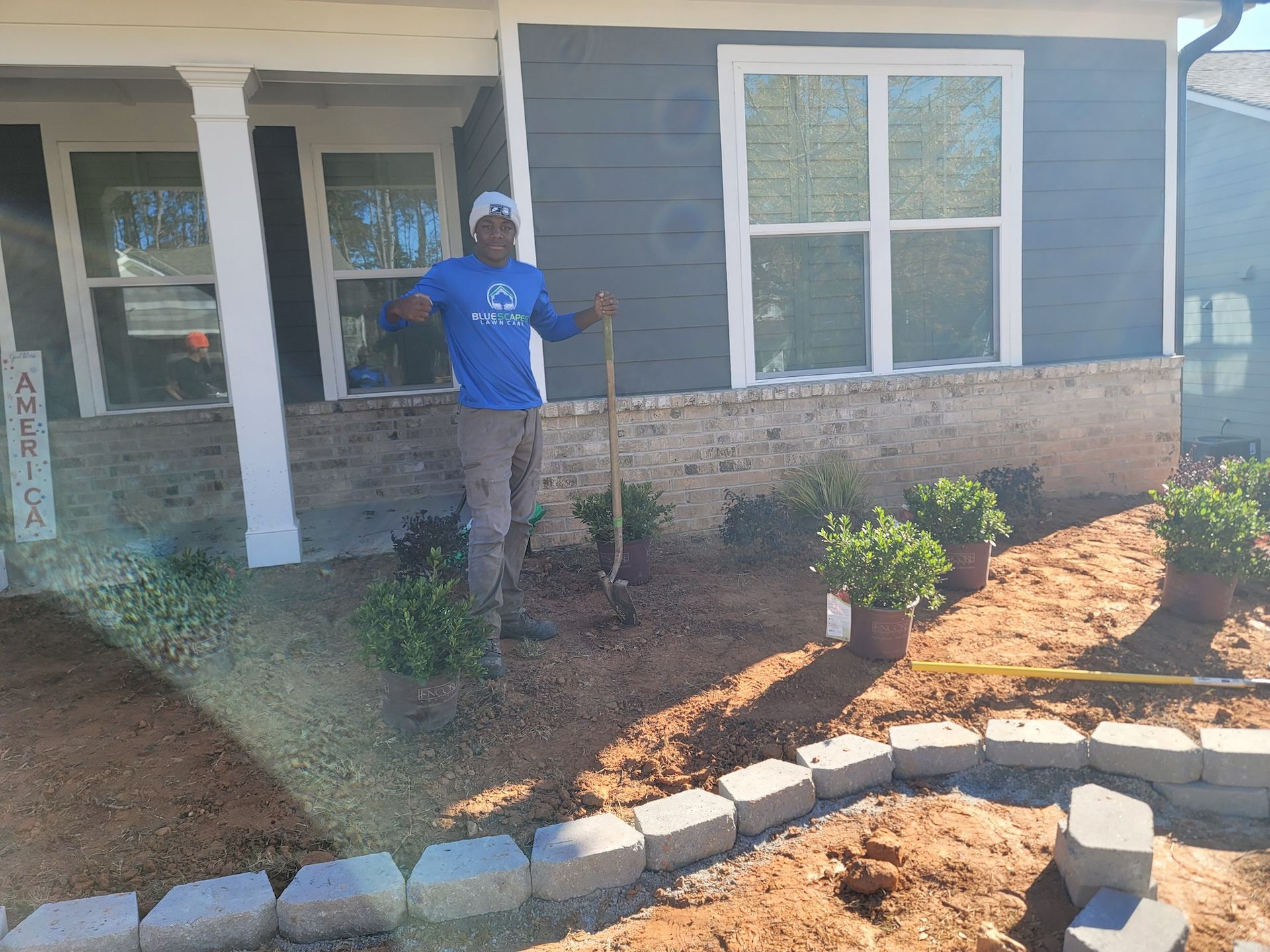 A man is standing in front of a house holding a shovel