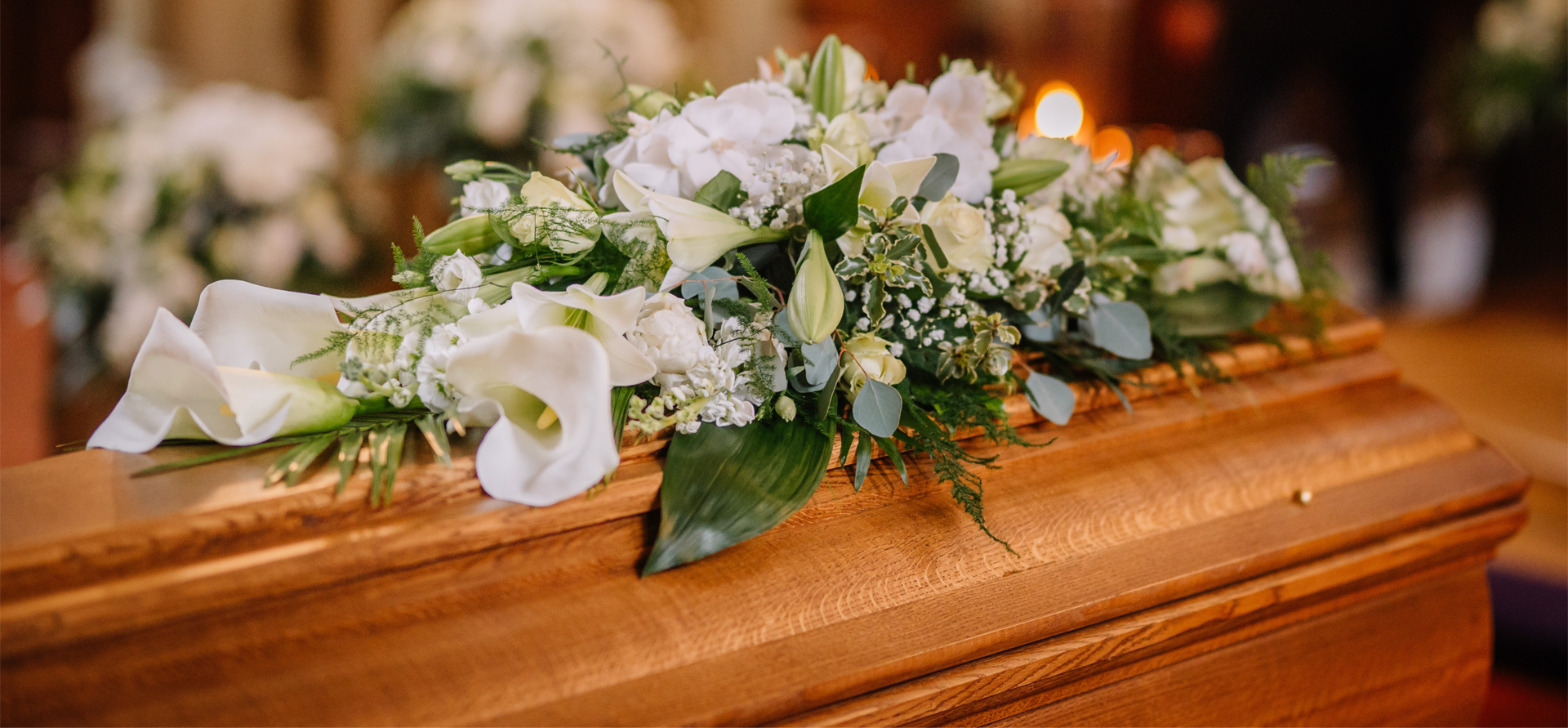 White flowers arranged on a wooden casket at a funeral