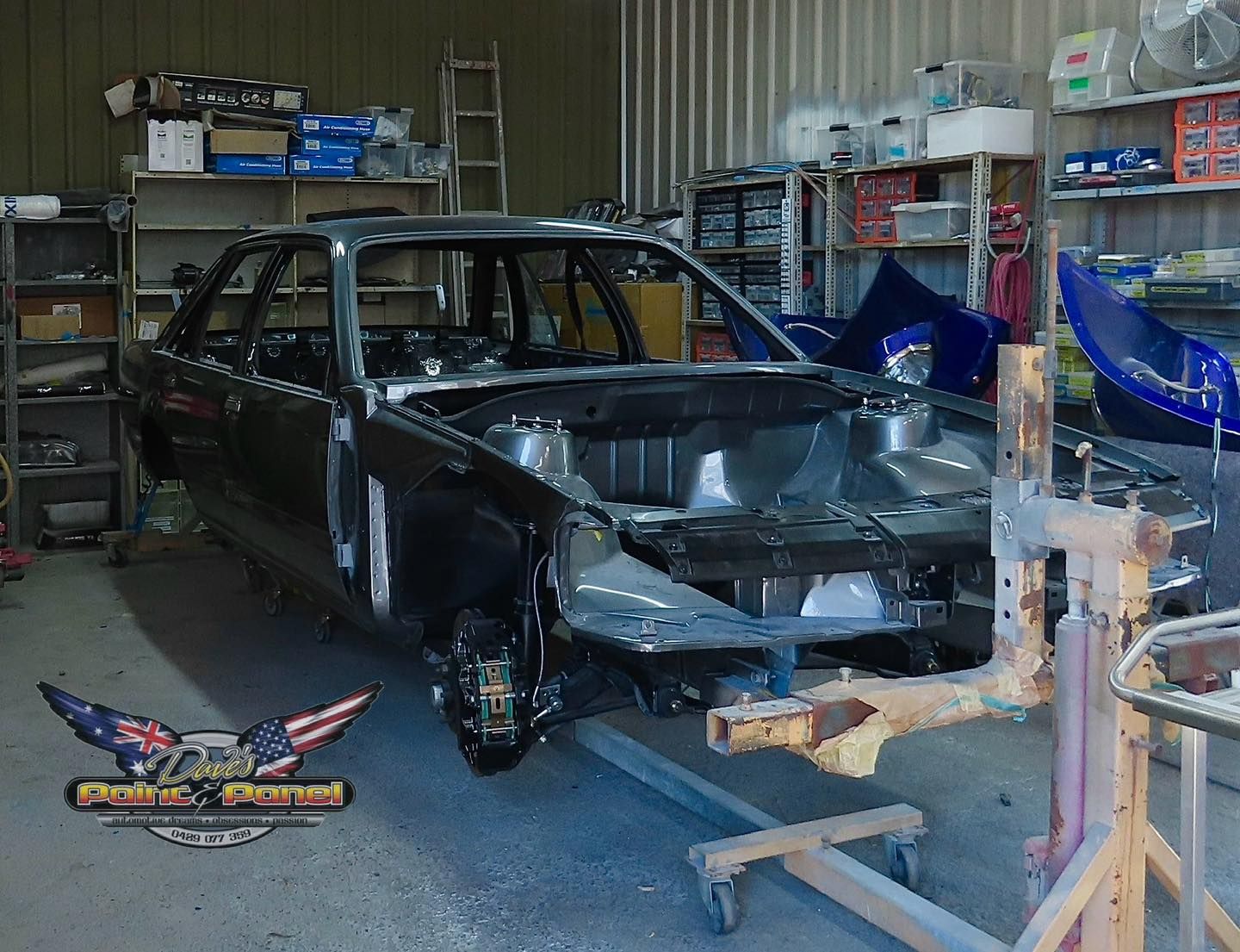 Black mini car in a garage covered with plastic sheeting for painting.