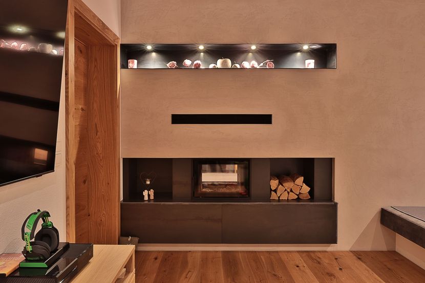 Modernes Wohnzimmer mit wandmontiertem Kamin, Holzvertäfelung und eingelassenen Regalen