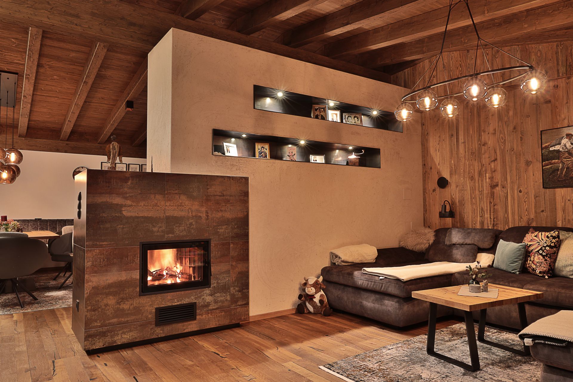 Gemütliches Wohnzimmer im Landhausstil mit Kaminfeuer, Ledersofa, Holzdecke und warmer, stimmungsvoller Beleuchtung.