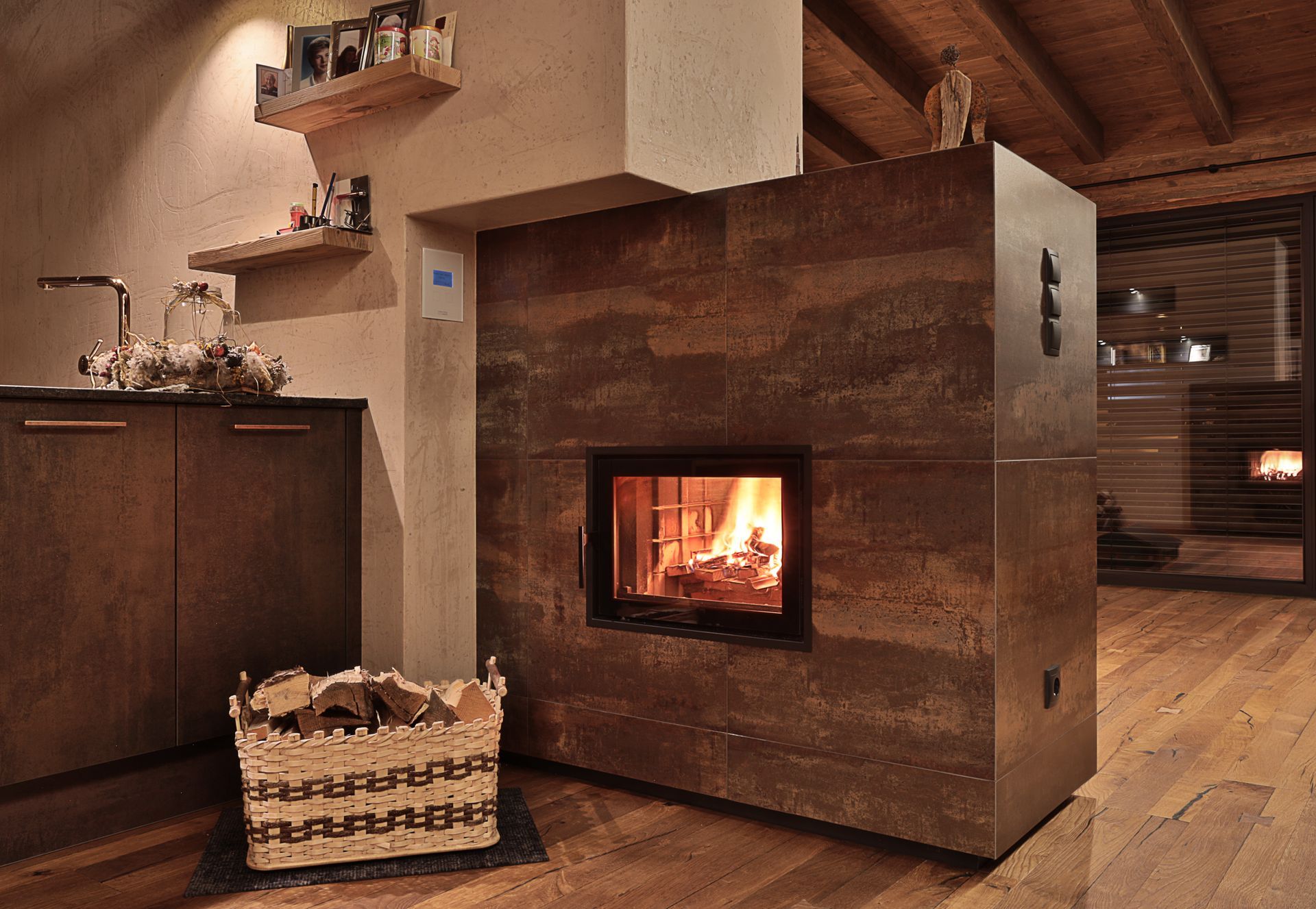 Gemütliches, holzgetäfeltes Zimmer mit modernem Kamin und einem Korb mit Brennholz auf dem Boden.