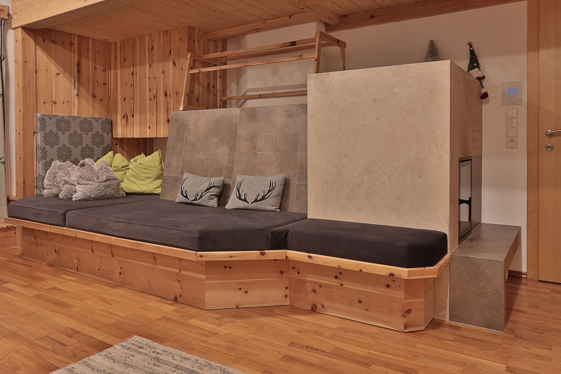 Moderne Holznische mit eingebauter Bank, grauen Kissen, Polstern und einer kleinen Trittstufe