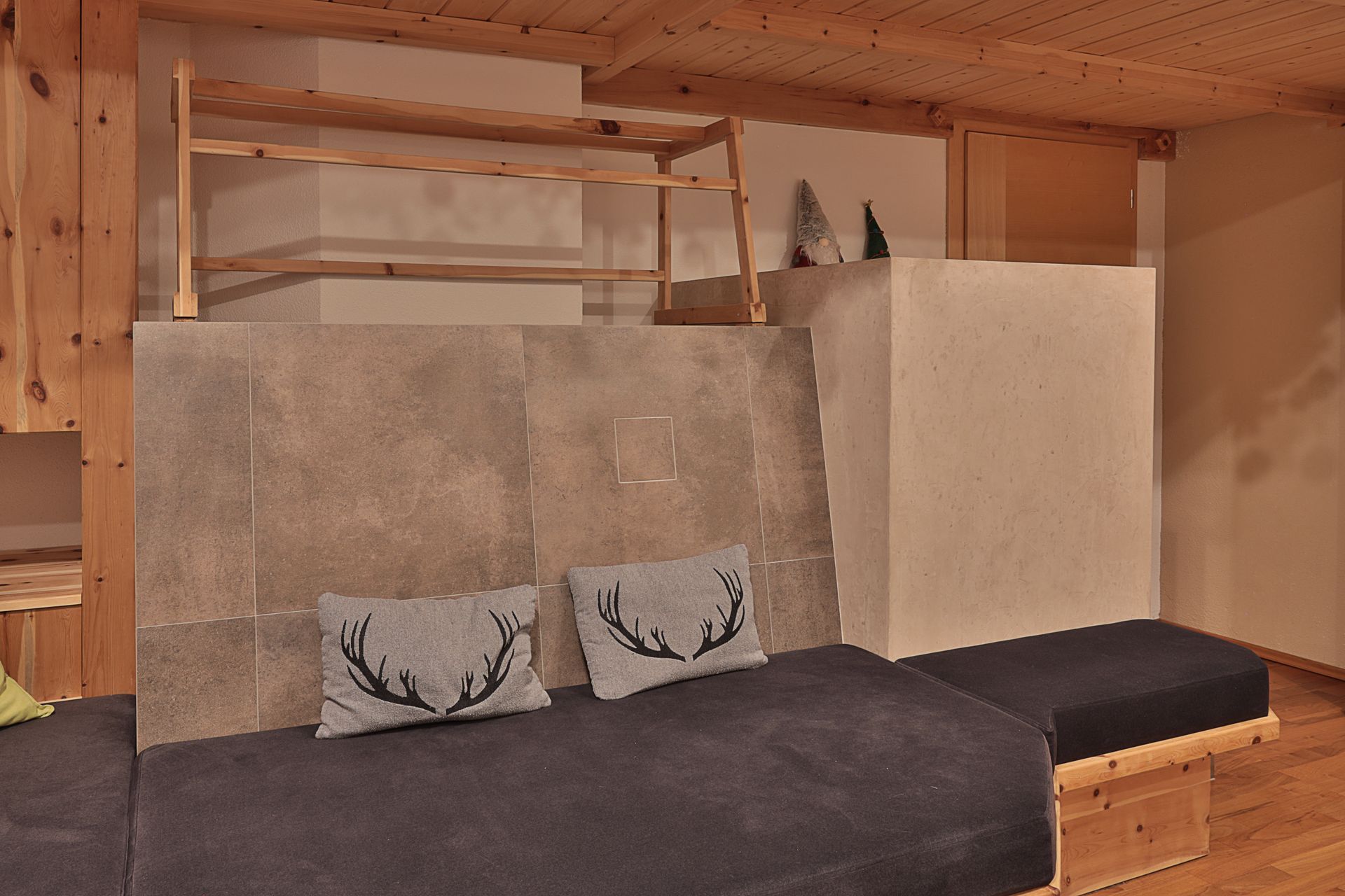 Modernes Loft-Interieur mit dunklem Sofa, Geweihkissen, Holzregalen und grauer Trennwand