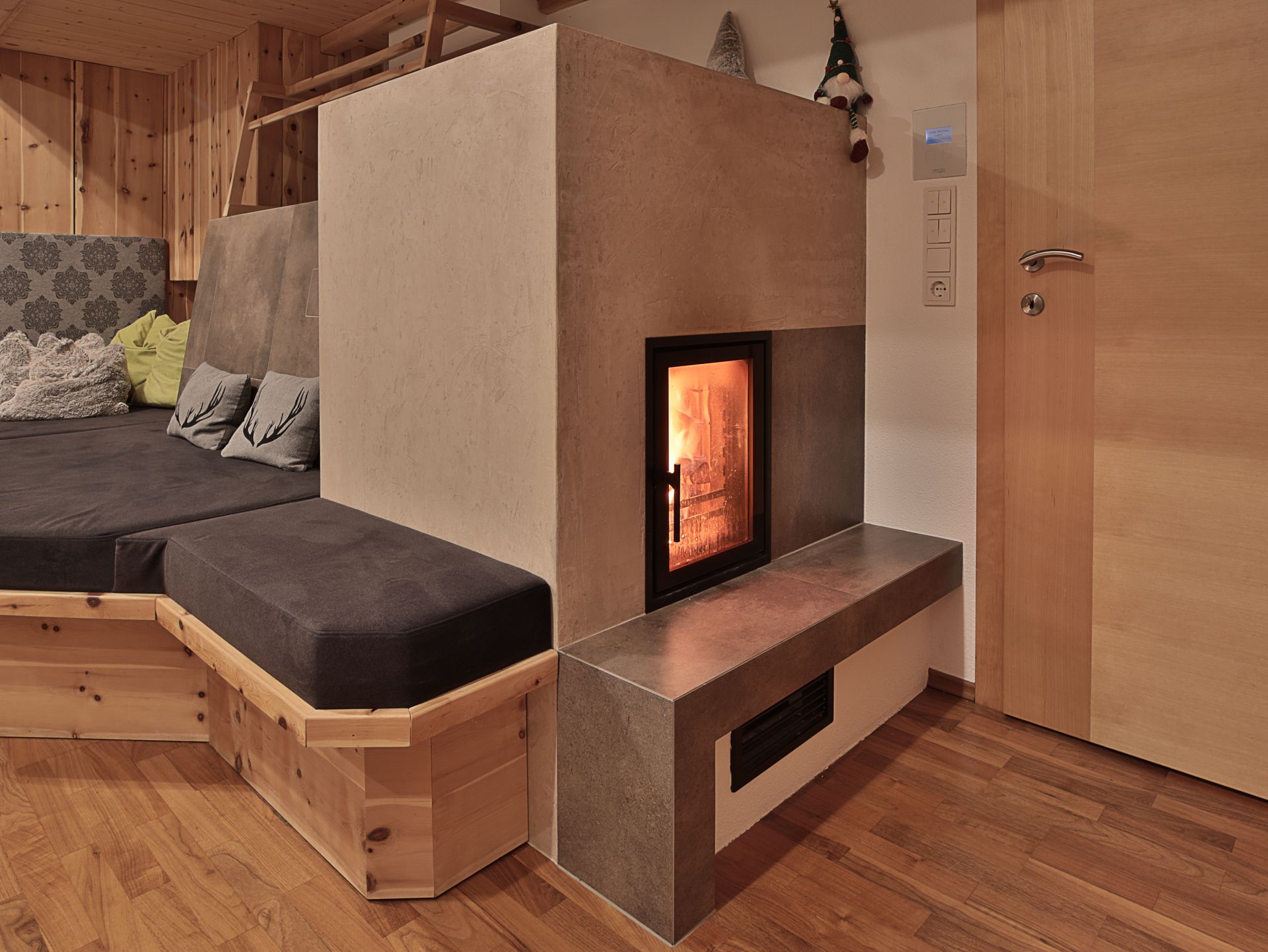 Kleines Wohnzimmer mit modernem Kamin, Holzbank, grauem Sofa und holzgetäfelten Wänden