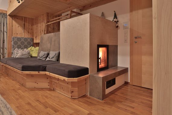 Holzgetäfeltes Zimmer mit eingebauter Holzbank und modernem Kamin neben einer Glastür