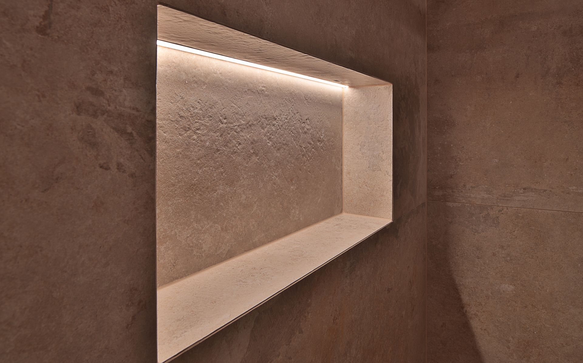 Strukturierte beige Wand mit einem eingelassenen, beleuchteten Regal und sanfter, warmer Beleuchtung