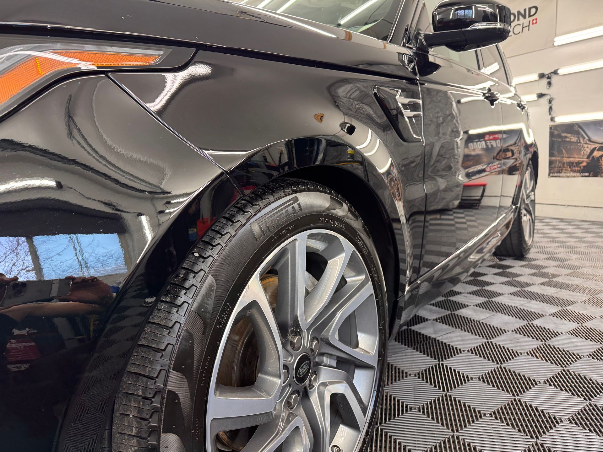A black range rover sport is sitting on a checkered floor in a showroom.