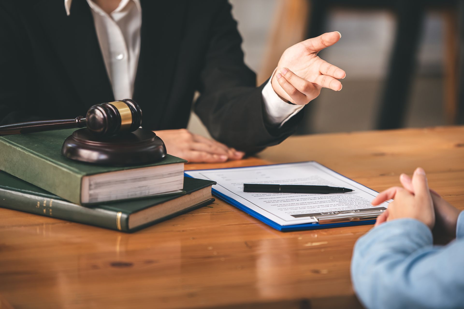 Lawyer and client discussing a case at a wooden desk with gavel, books, and paperwork