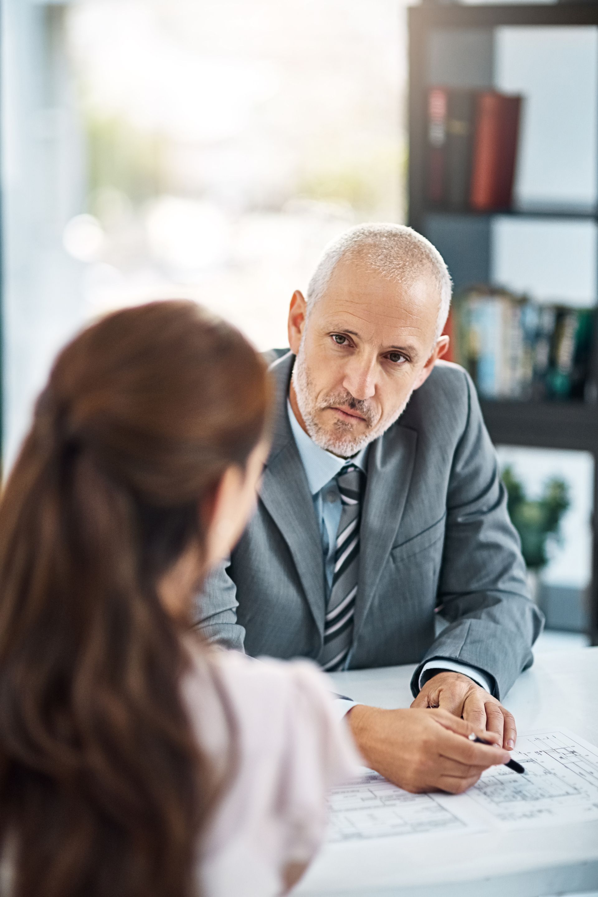 Two people in an office meeting, with one writing notes across a table.