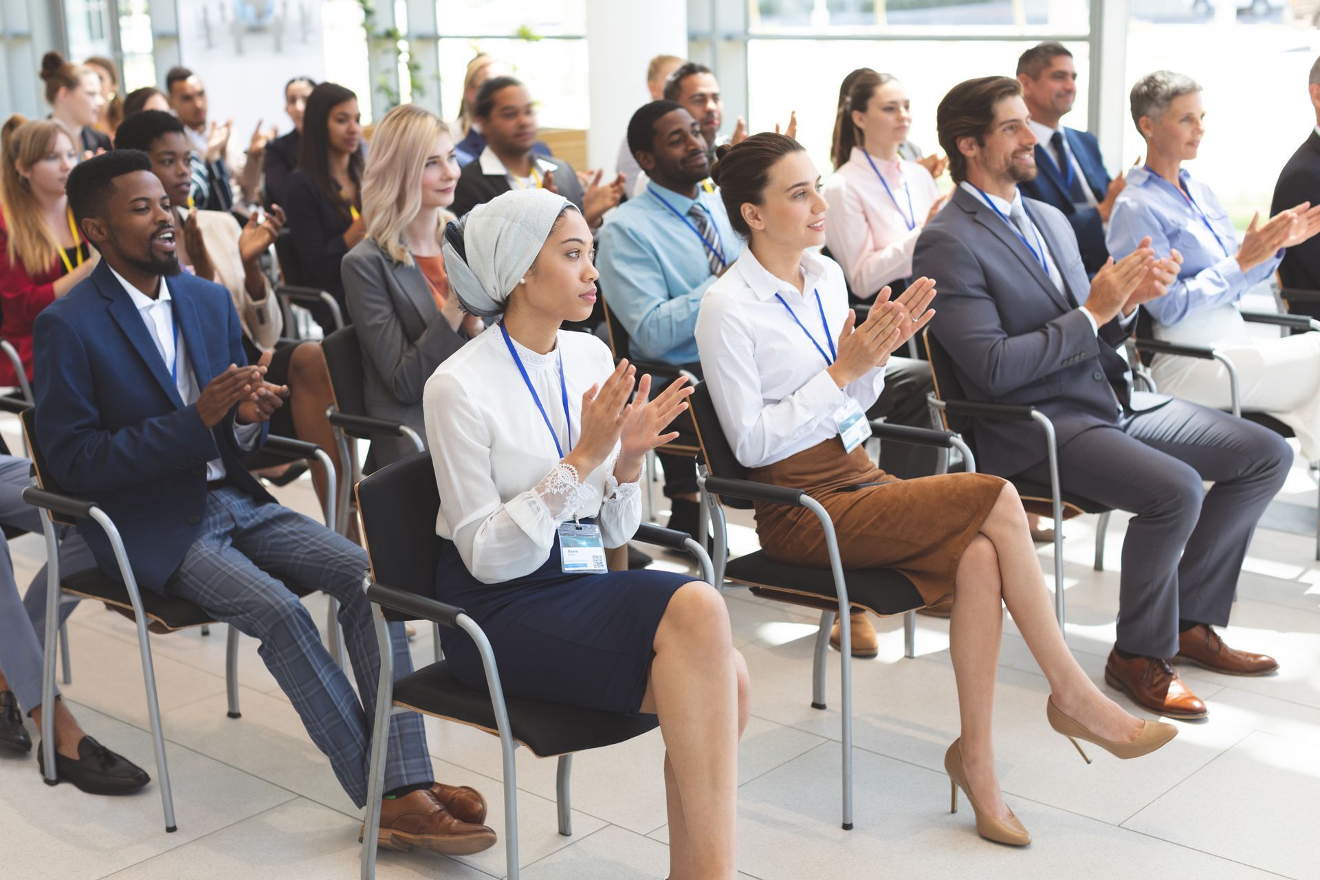 Audience seated at a bright conference, applauding and listening attentively.