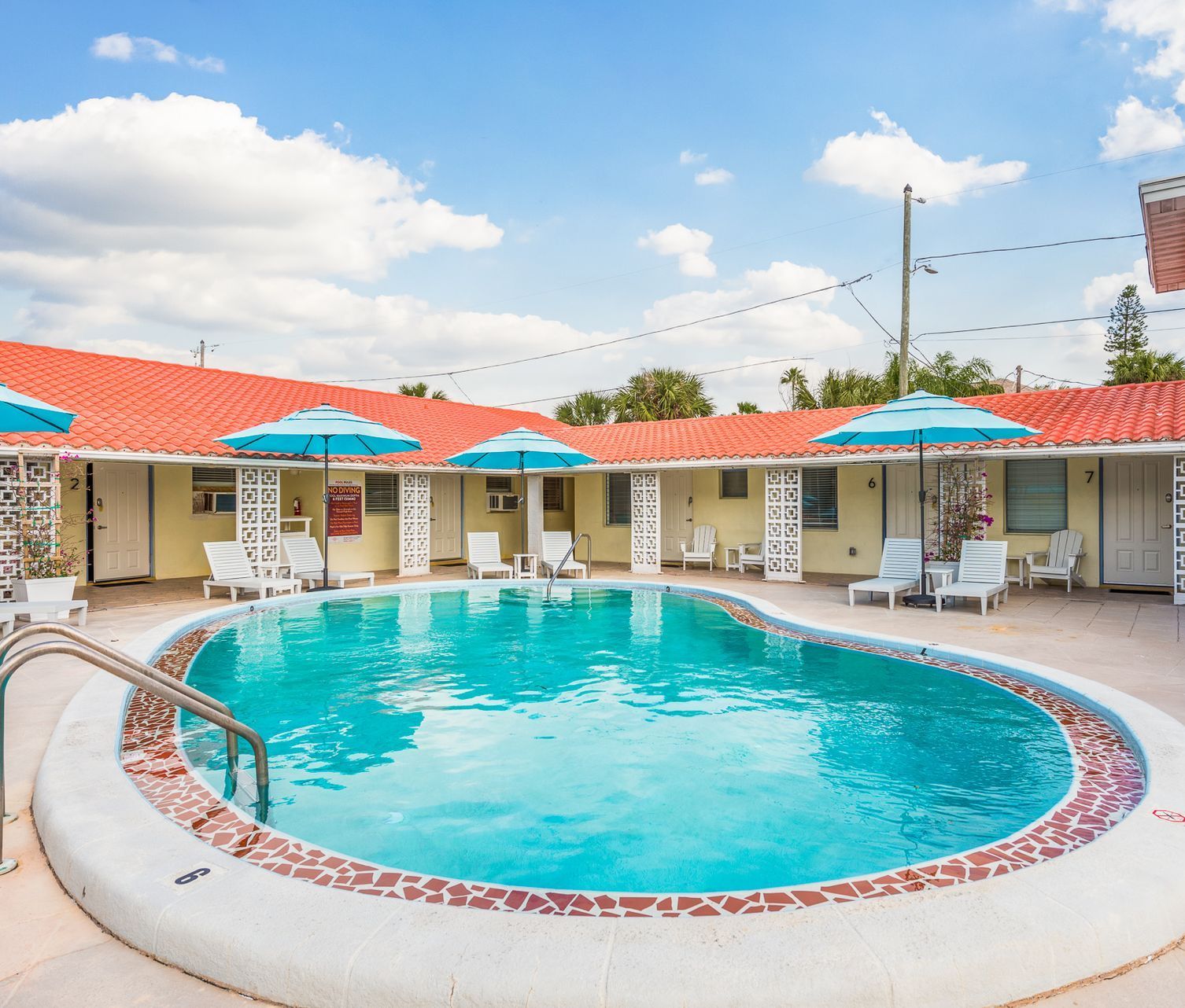 A large swimming pool surrounded by chairs and umbrellas