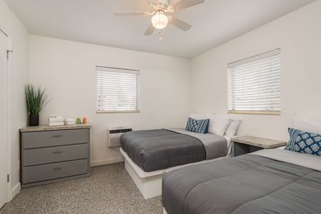 A bedroom with two beds and a ceiling fan