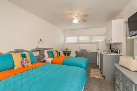 A hotel room with two beds and a kitchen.