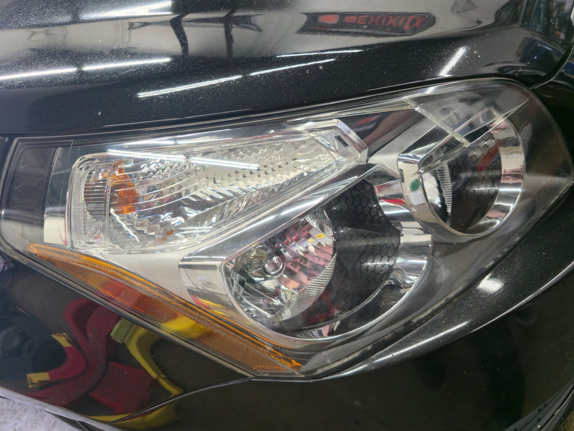 Close-up of a car's front headlight with clear lens and amber turn signal.