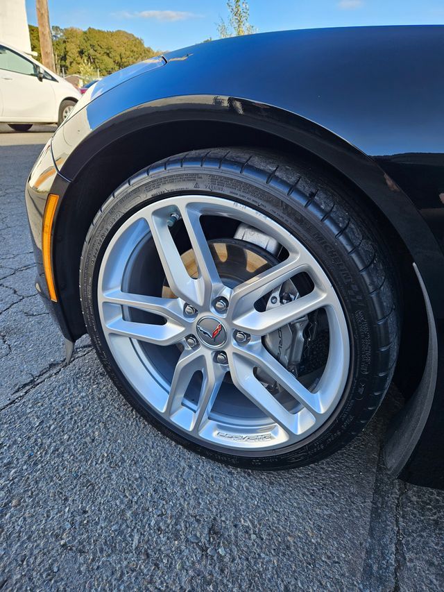 Close-up of a silver alloy wheel and tire on a black sports car parked on pavement