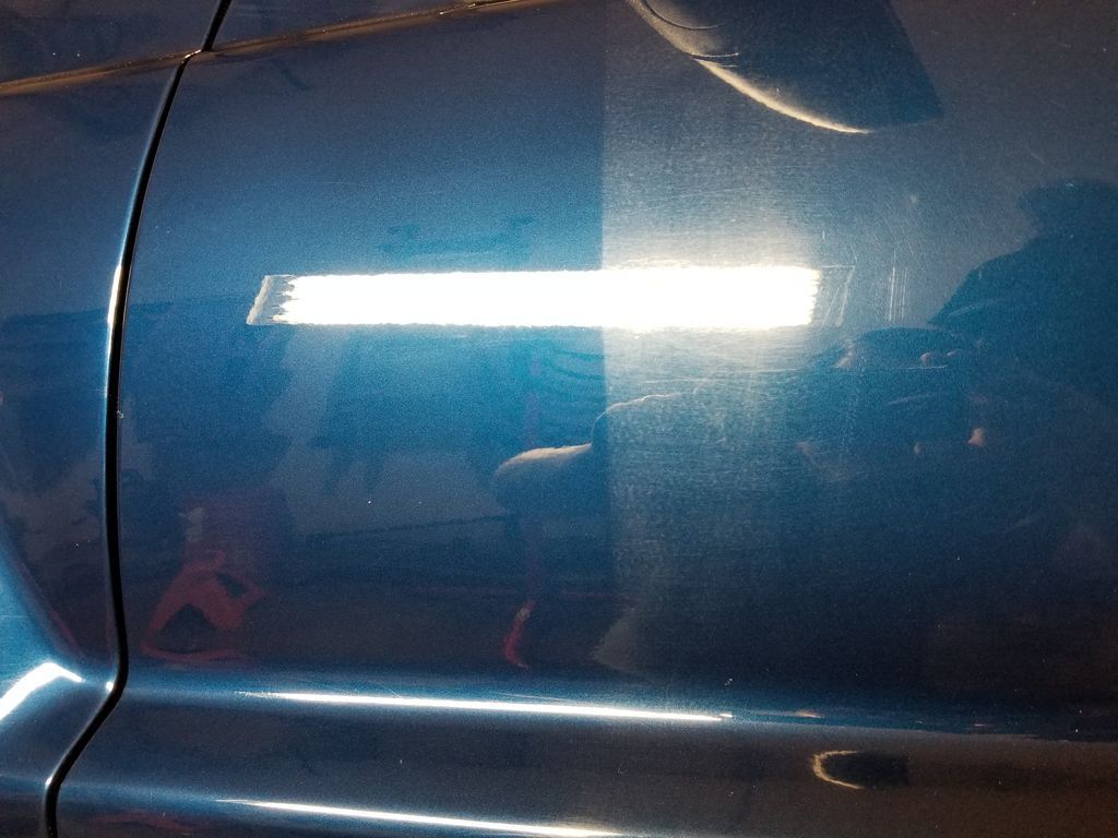 Blue car door with bright light reflection on the glossy paint