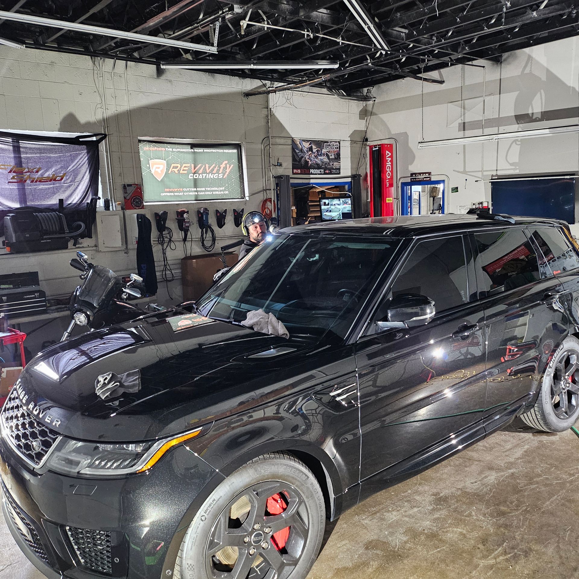 Black SUV with red brake calipers parked inside an auto garage or showroom.
