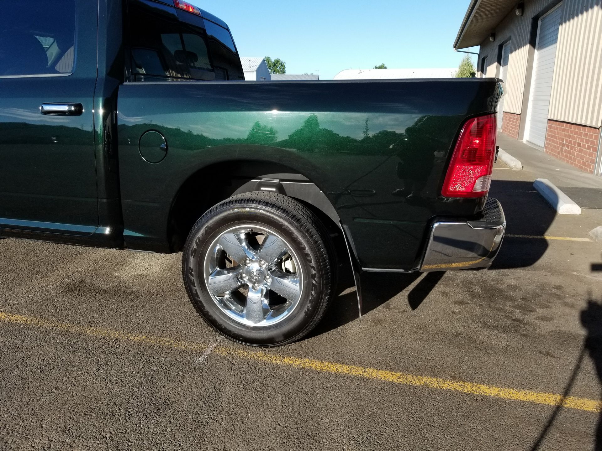 Black pickup truck parked in a lot, showing the rear wheel and tail light.