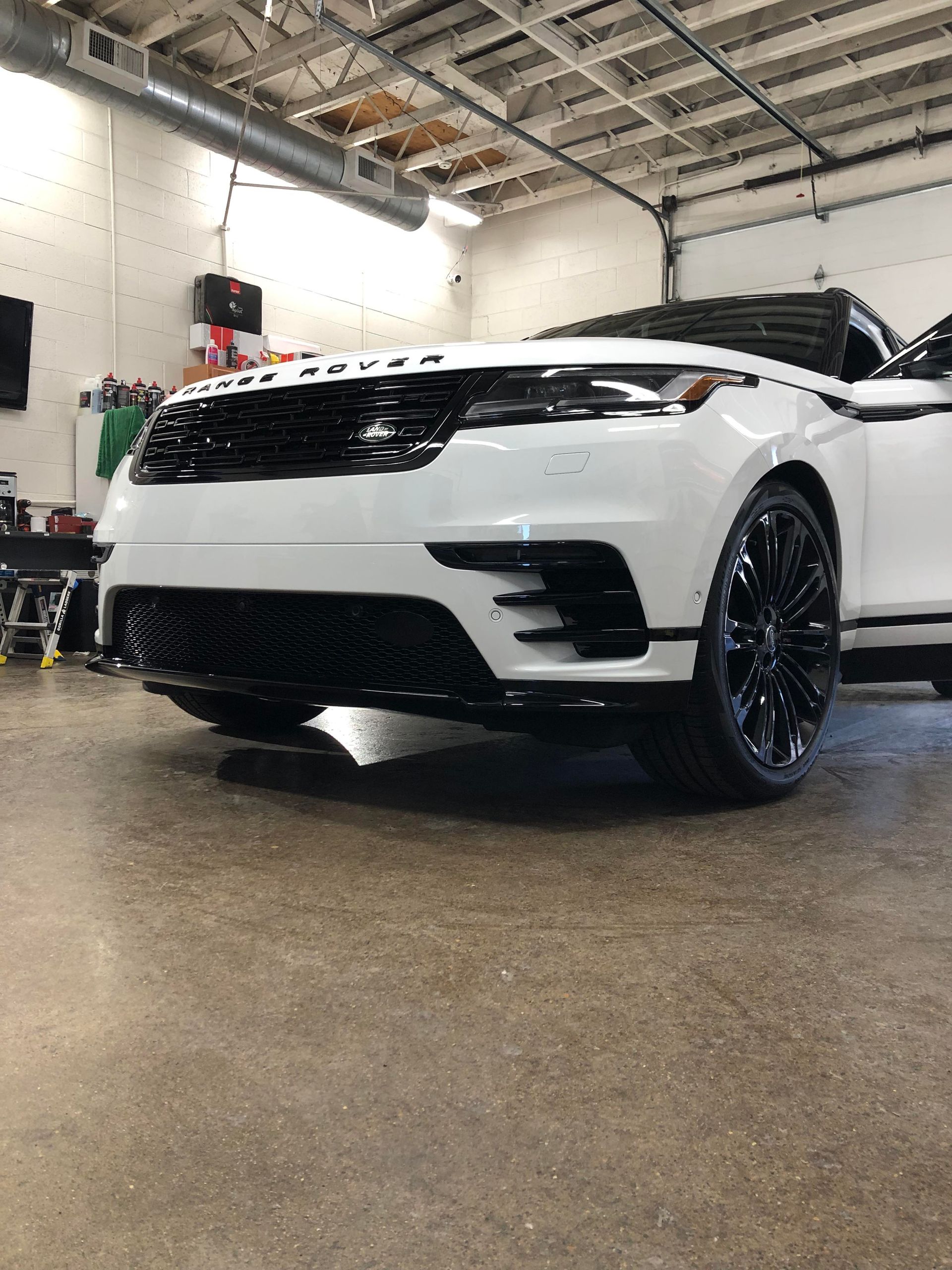 White Land Rover SUV with black grille and wheels parked in a garage.