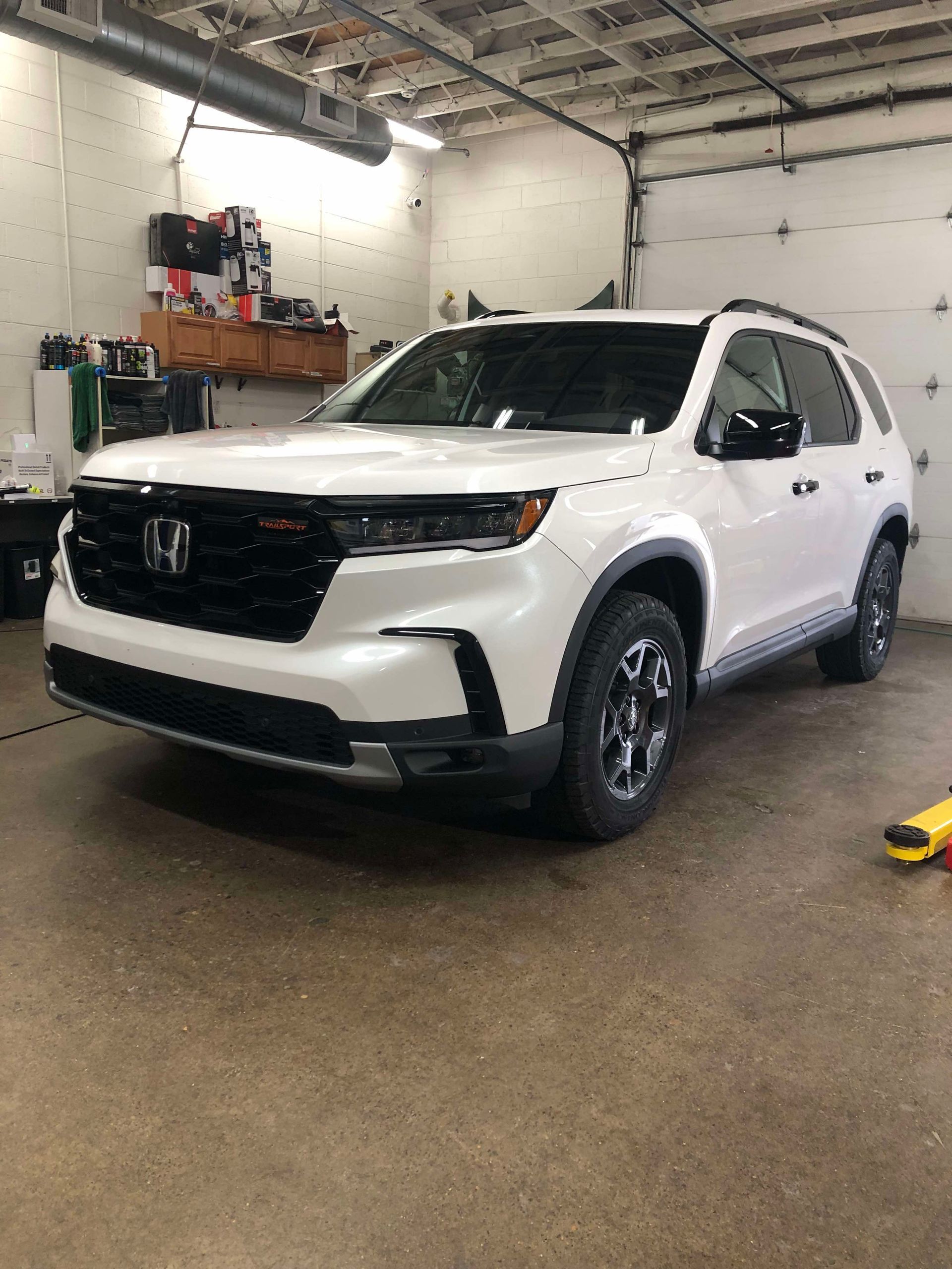 White SUV parked inside a garage with wet floor and wall shelves in the background