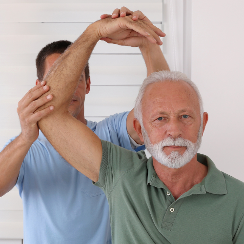 Two men stretching arms overhead in a bright room, one in a green polo and one in a blue shirt