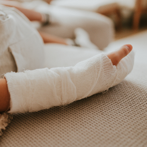 Wrapped foot in a white cast resting on a beige couch with pillows in the background