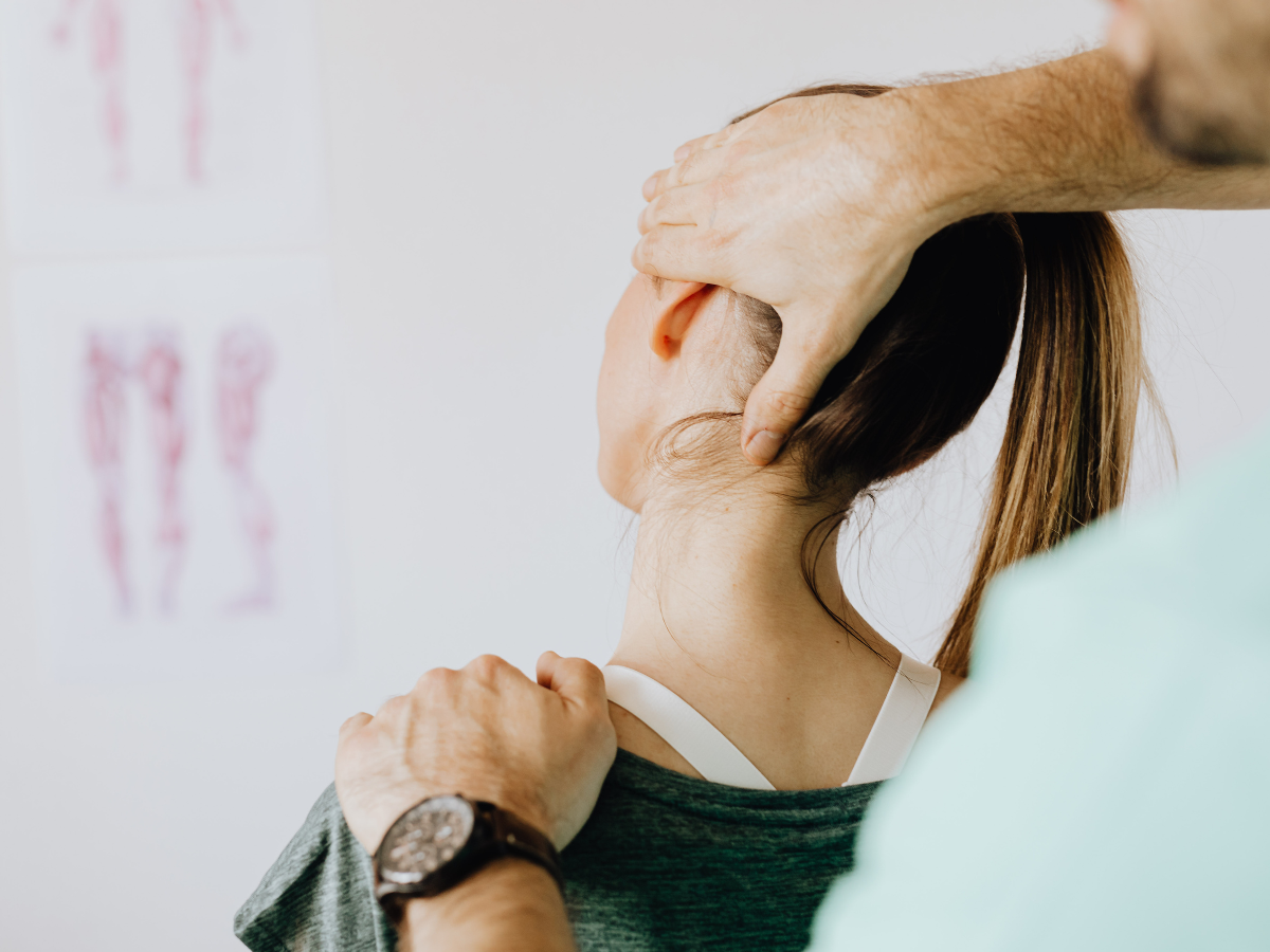 Hand gripping a person’s neck in a clinical setting, suggesting a neck adjustment or massage