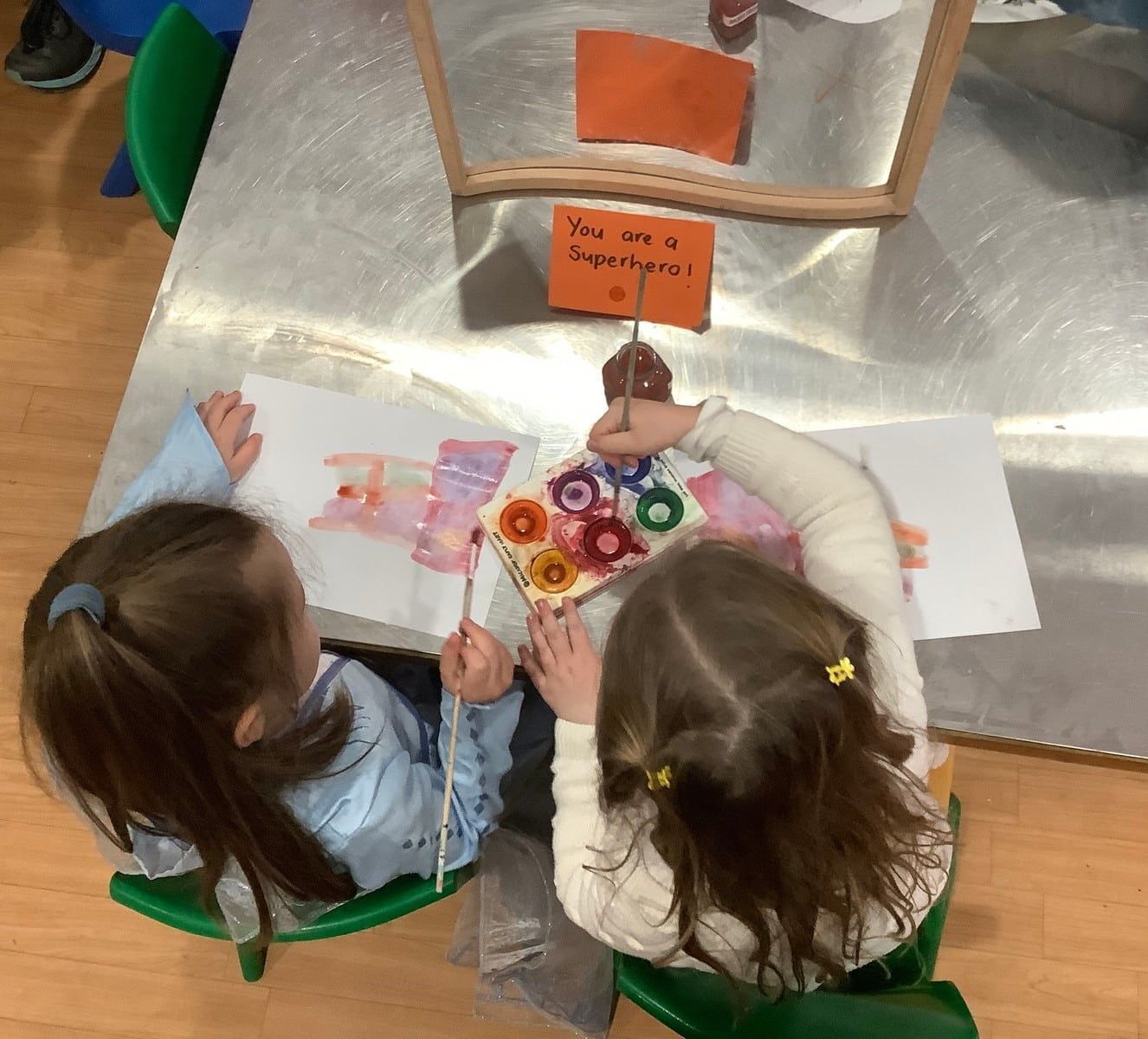 Little Boy Pointing Up — Fun & Supportive Childcare Centre in Wamberal, NSW Two Little Girls Are Sitting At A Table — Juniors At Wamberal in Wamberal, NSW