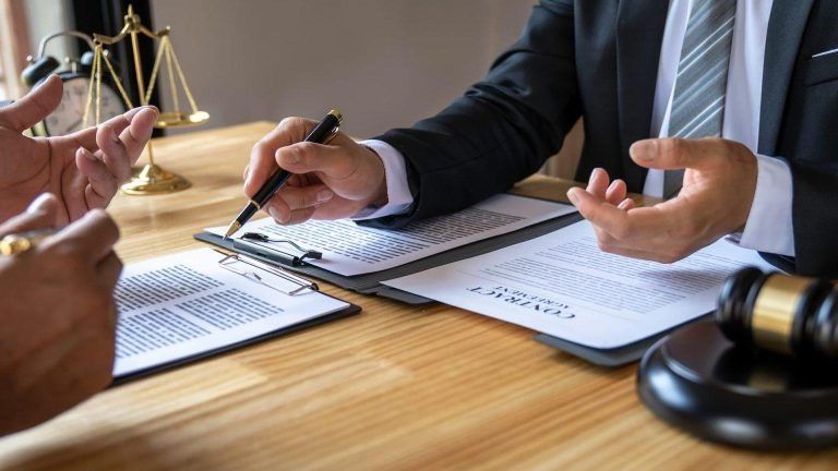 Person writing on a form at a wooden table with a pen