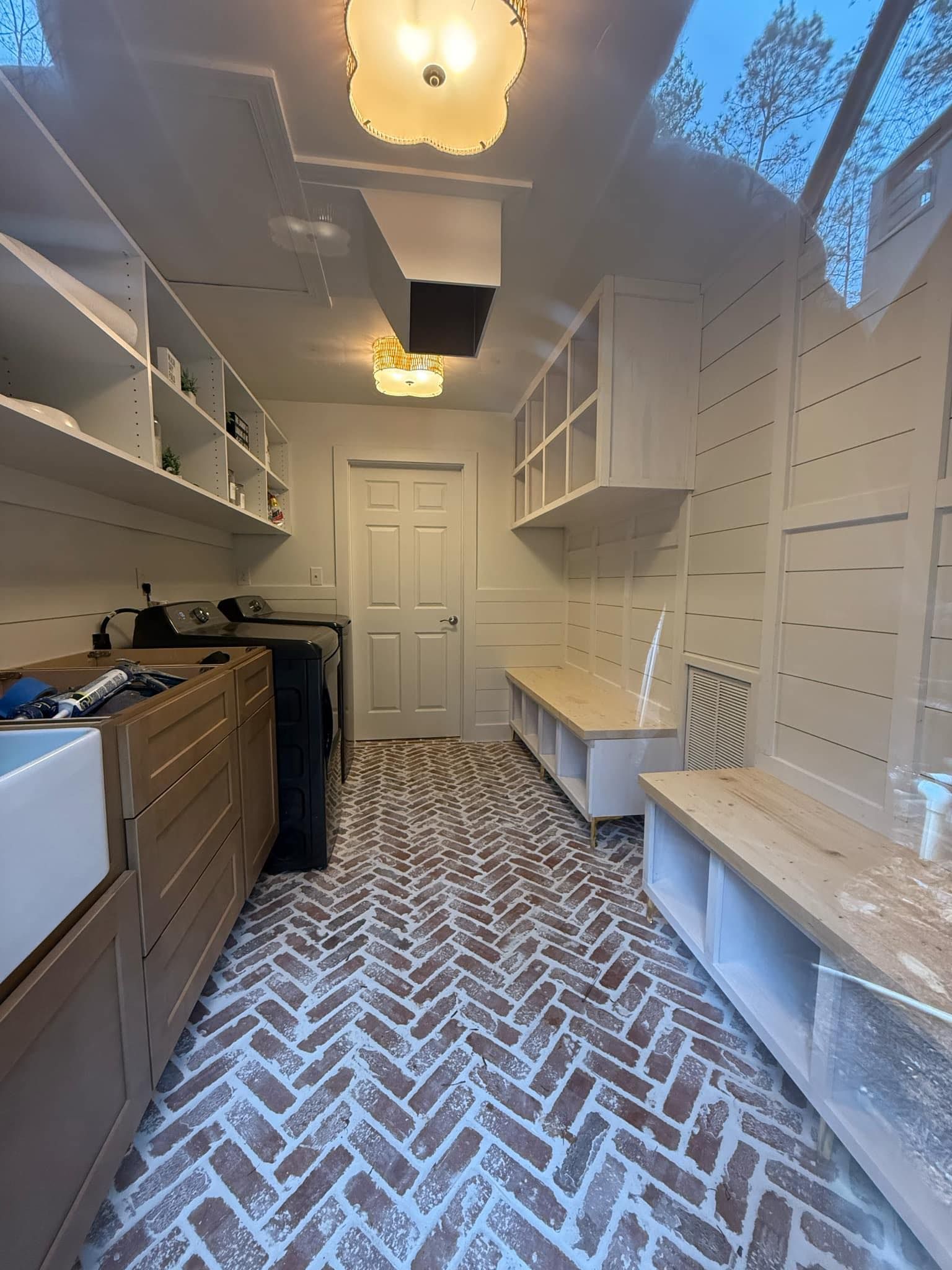 Laundry room with brick herringbone floor, white cabinetry, and a utility sink.