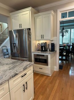 White kitchen with stainless steel stove and range hood. Cabinets, countertops, and wood floor.