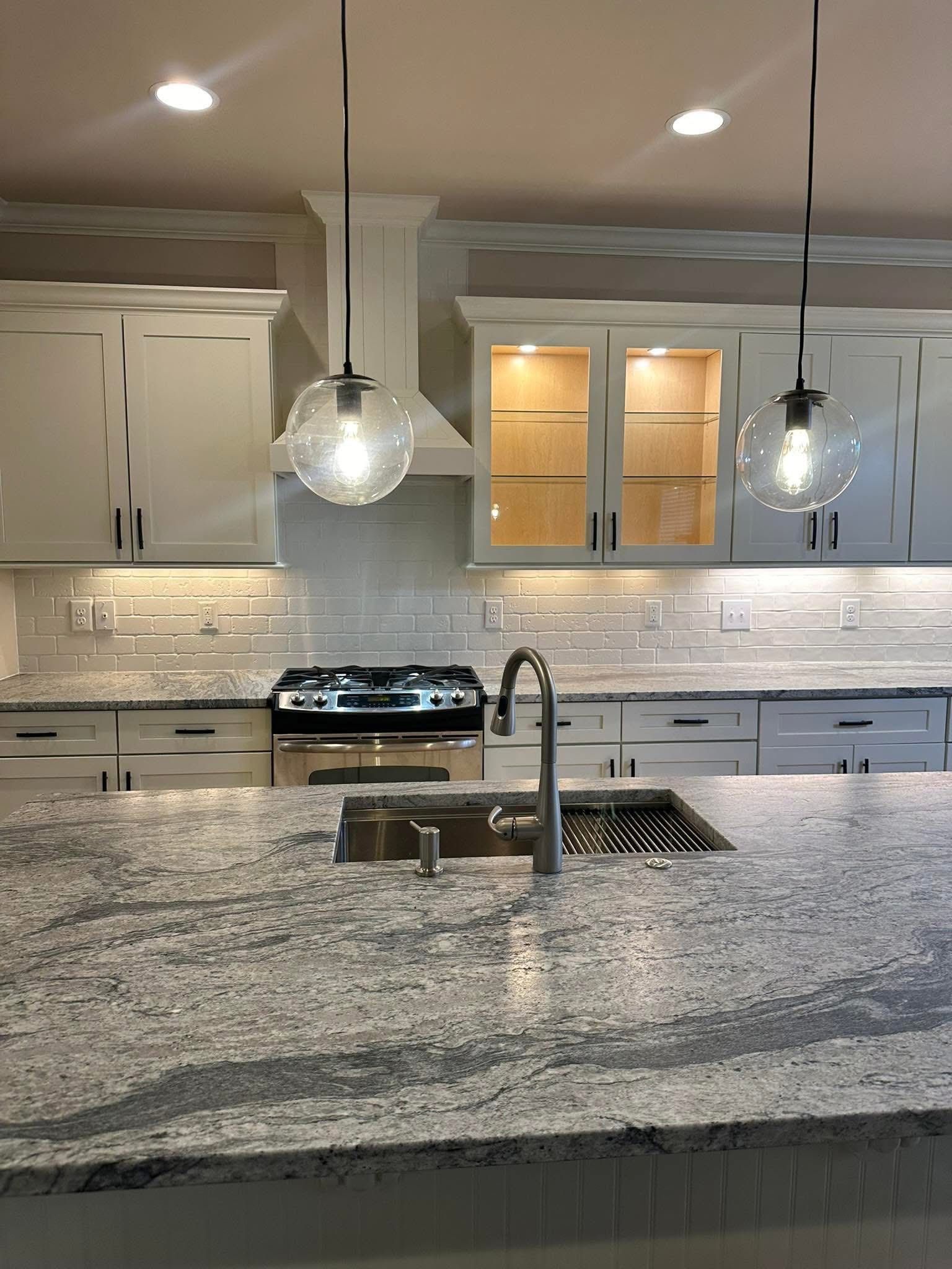 Kitchen with white cabinets, granite countertops, and two pendant lights.