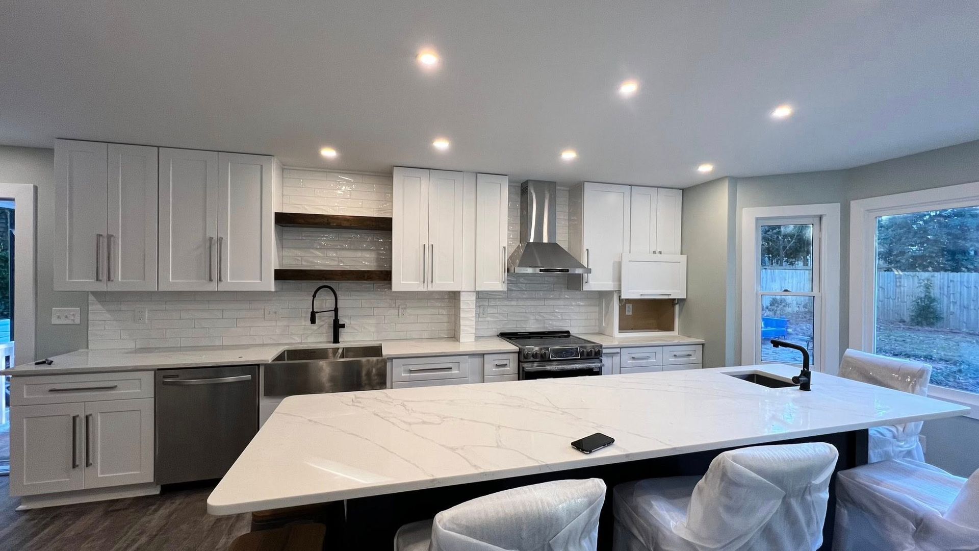 Modern kitchen with white cabinets, stainless steel appliances, and large island with seating.