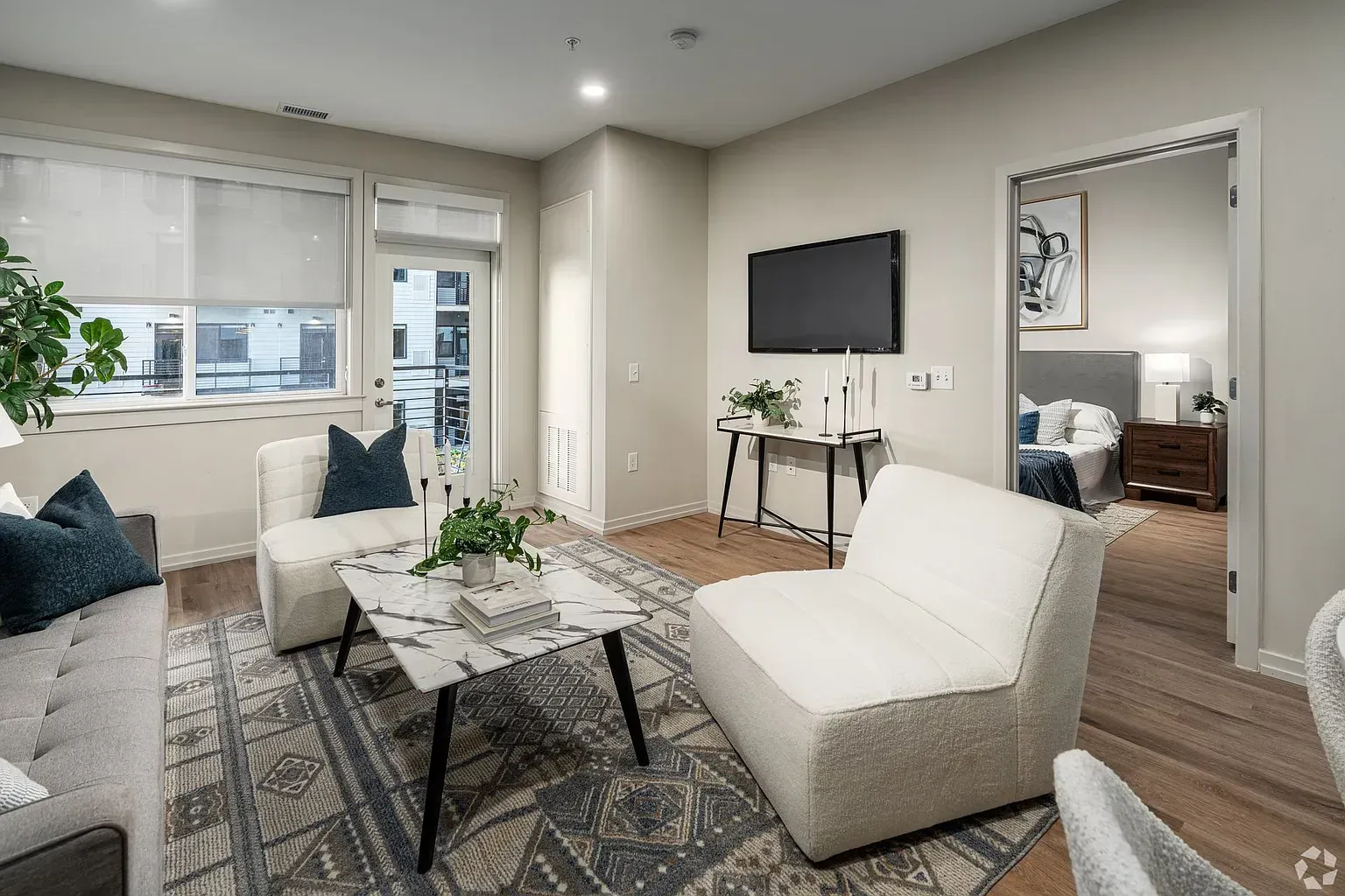 Photo of a living room with plenty of natural light and a bedroom in the background