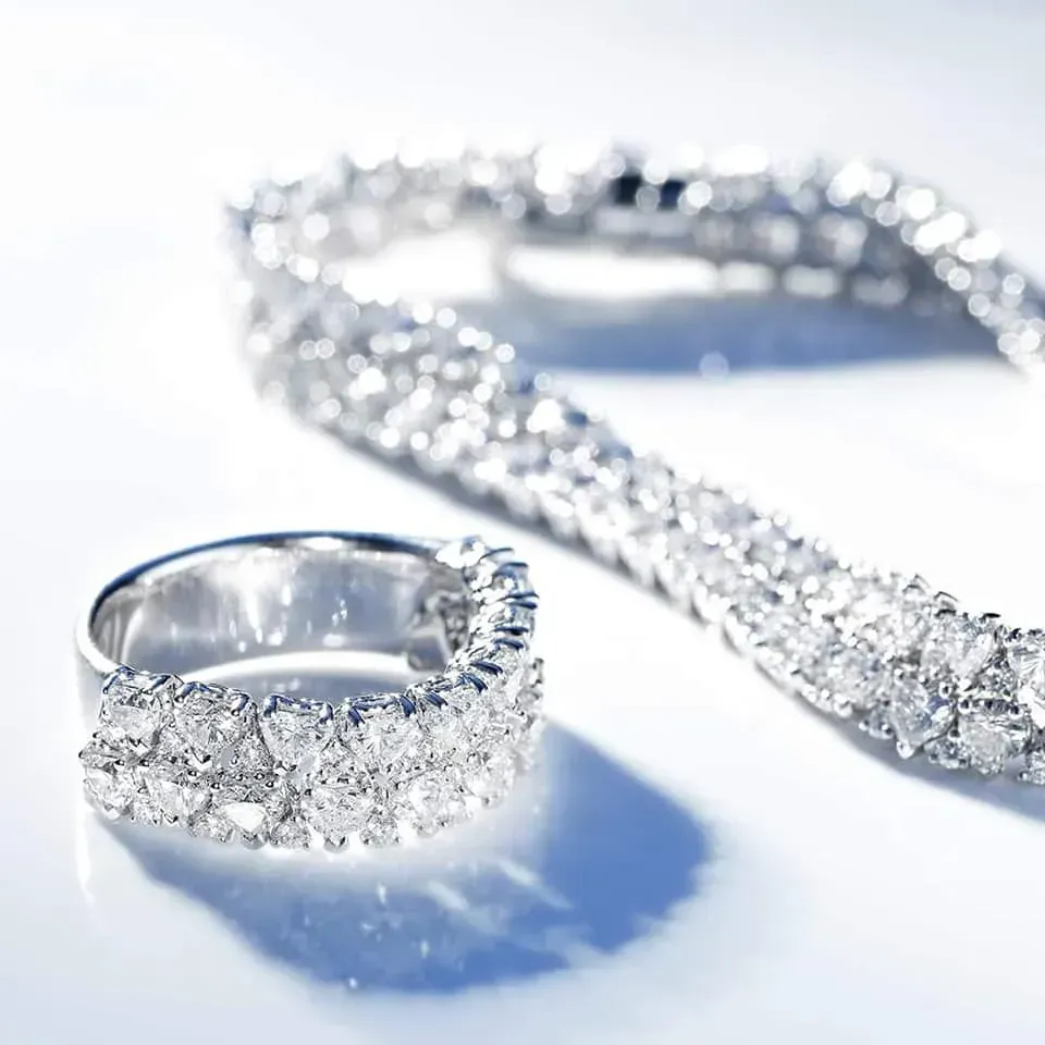 Anello e bracciale con diamanti su superficie bianca, scintillanti.