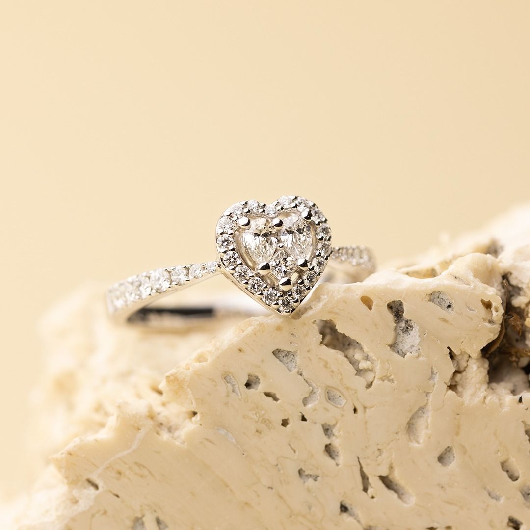 Anello con diamante a forma di cuore con alone su pietra chiara testurizzata.