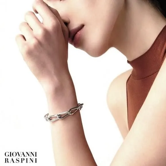 Donna con un braccialetto a maglie d'argento, braccia incrociate e top marrone.