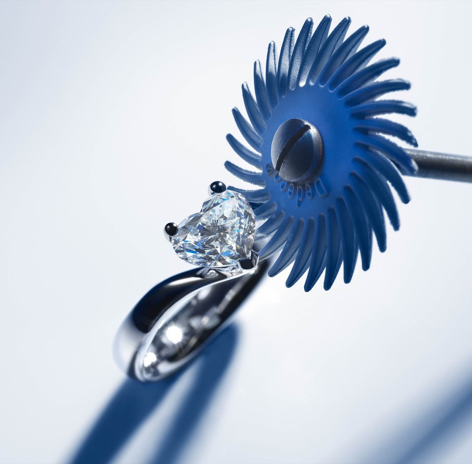Anello con diamante a forma di cuore lucidato con una piccola mola blu.