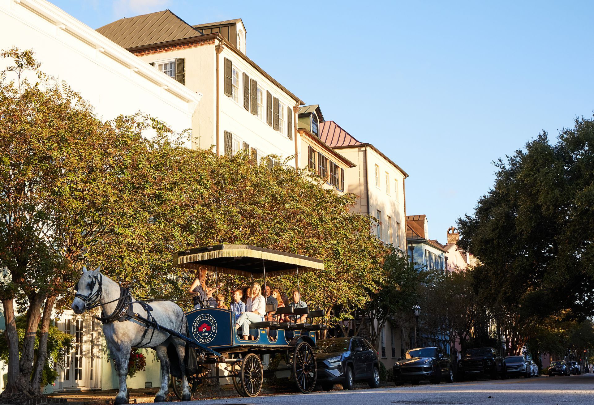 A horse drawn carriage carrying people down a city street