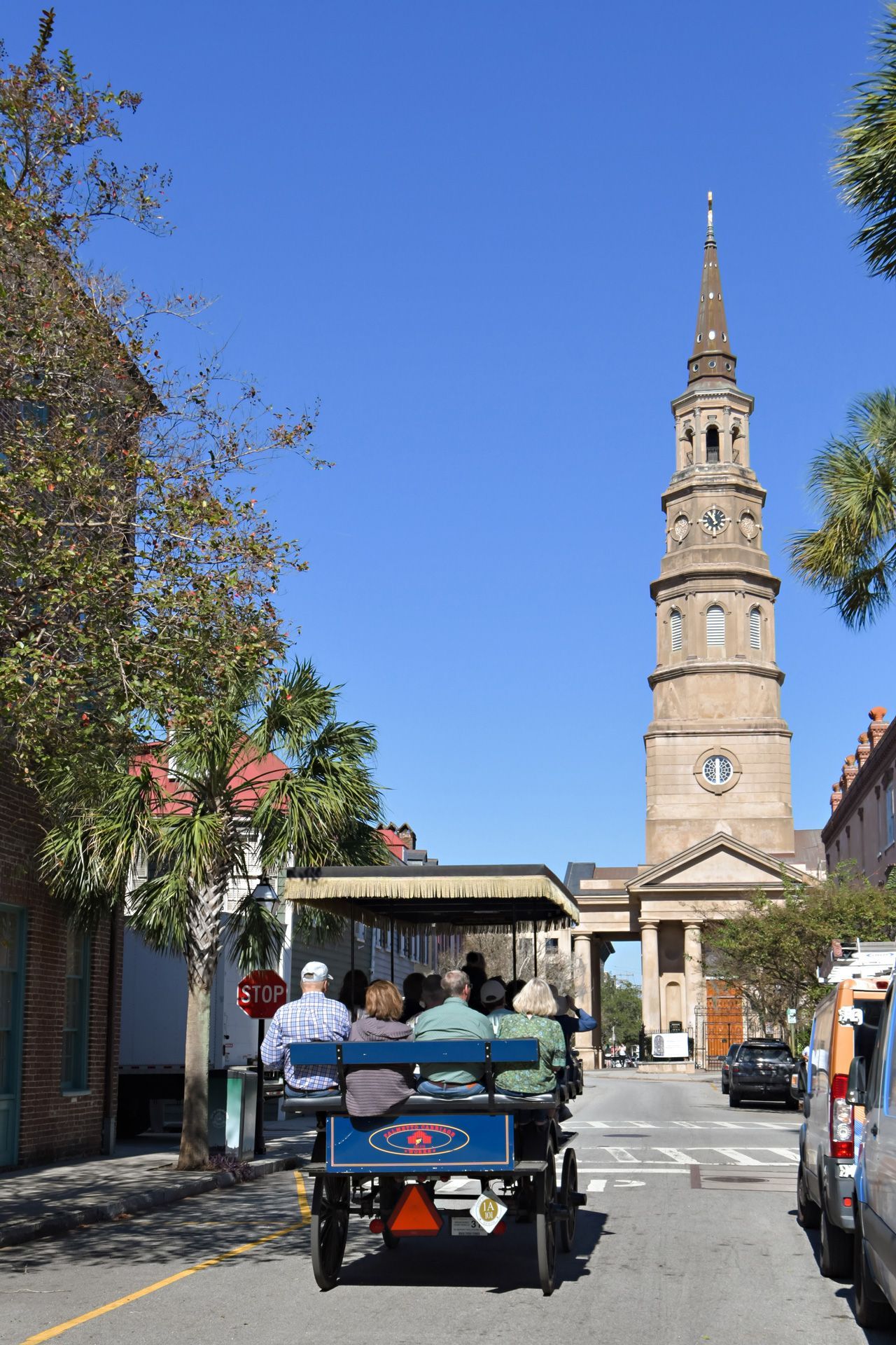 A group of people are riding a horse drawn carriage down a street with a clock tower in the background