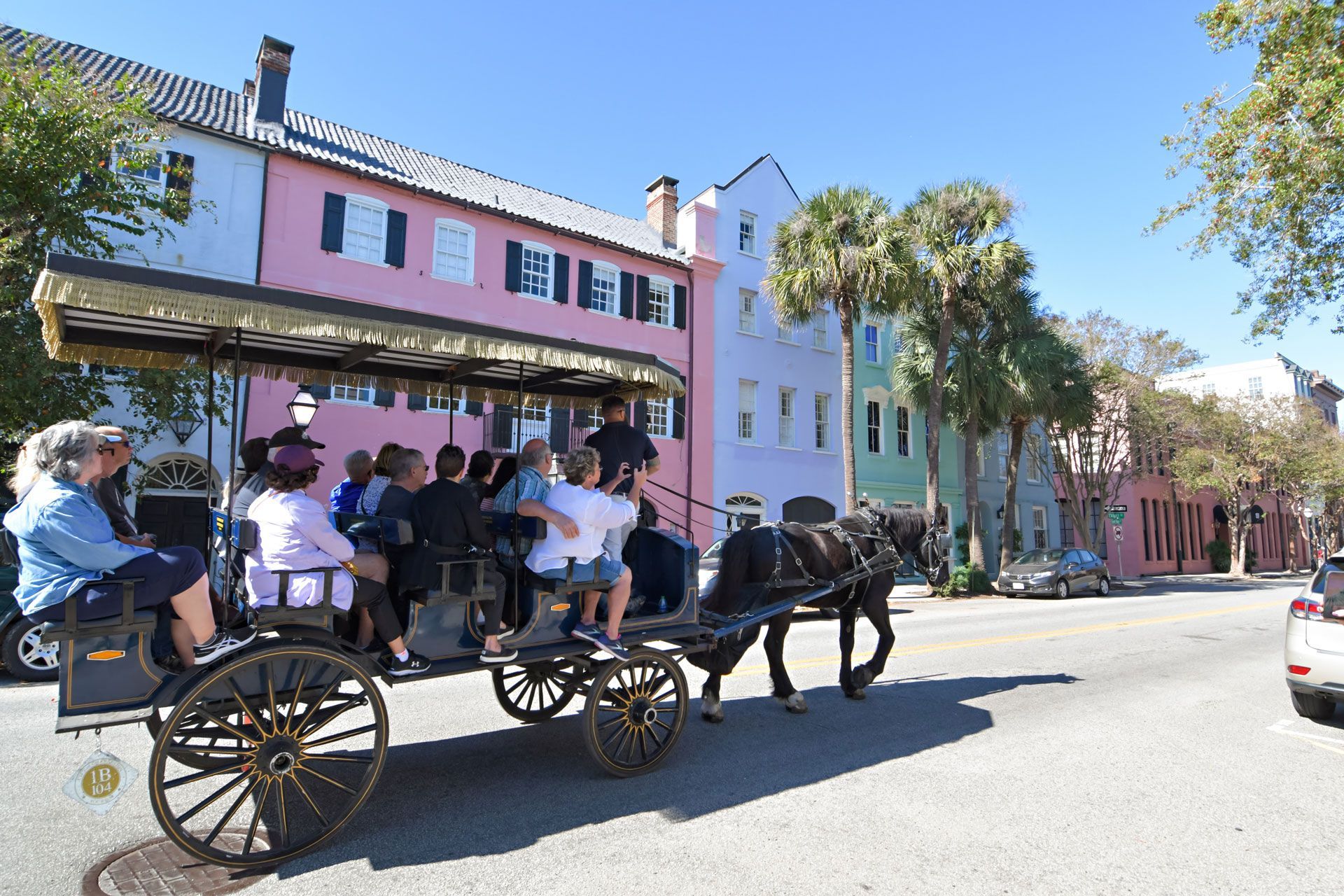 A group of people are riding in a horse drawn carriage down a street.