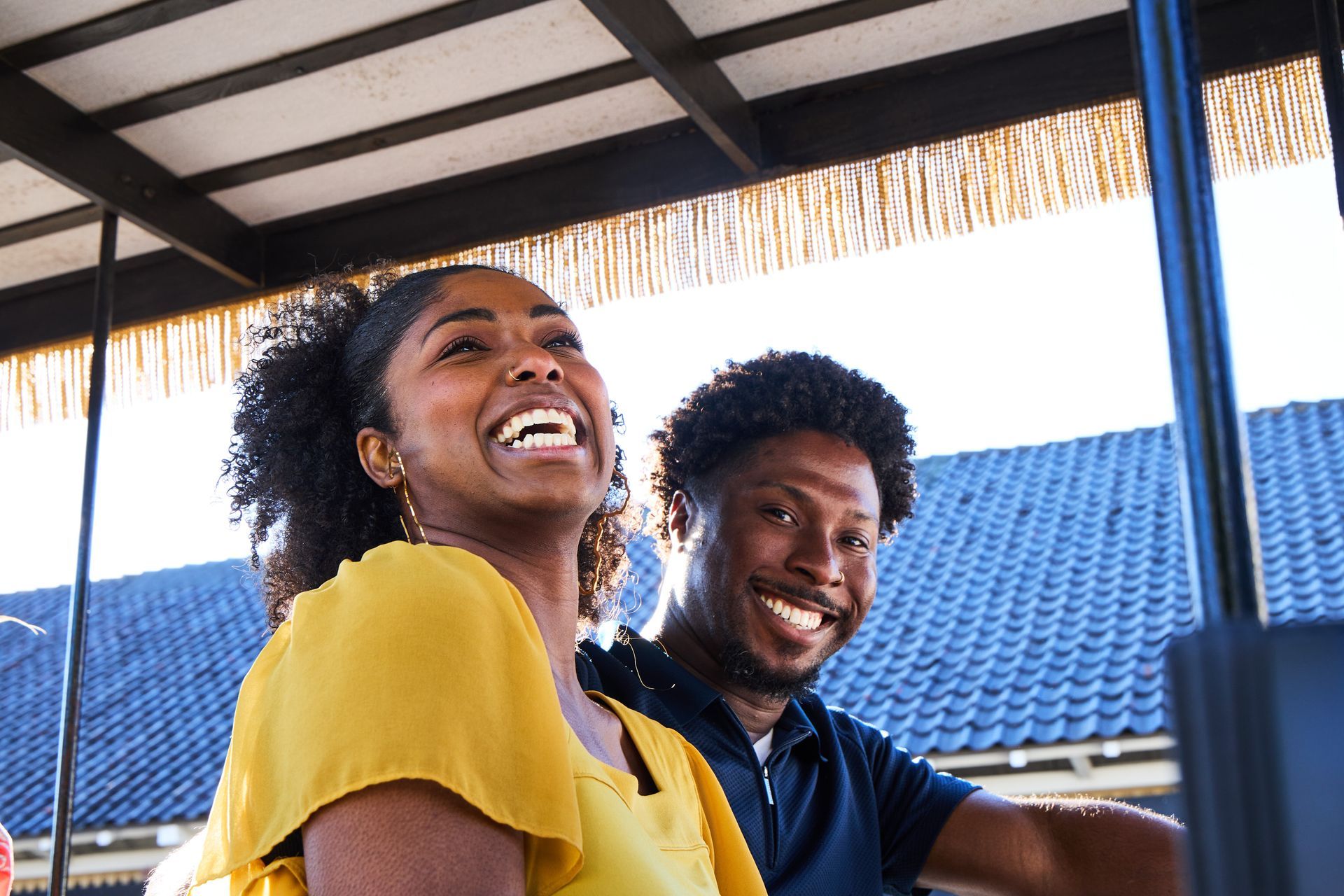A man and a woman are sitting on a golf cart and smiling.