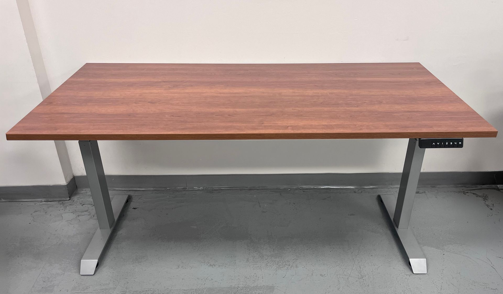 Brown rectangular standing desk with gray legs and a control panel on the right.