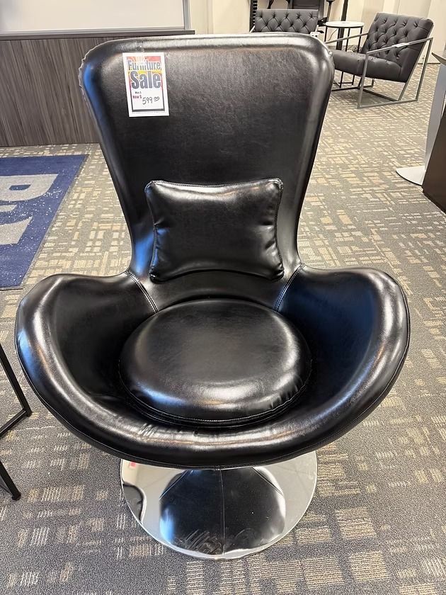 Black leather swivel chair with a lumbar pillow, on a chrome base. A